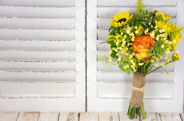 sunflower and orange bouquet wrapped in burlap on whitewashed wood