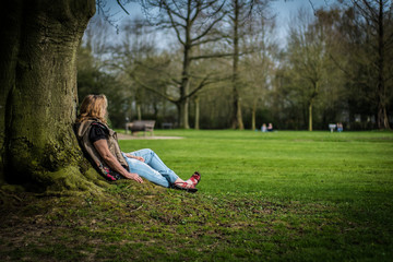 Women sitting under old tree in a green and summery park