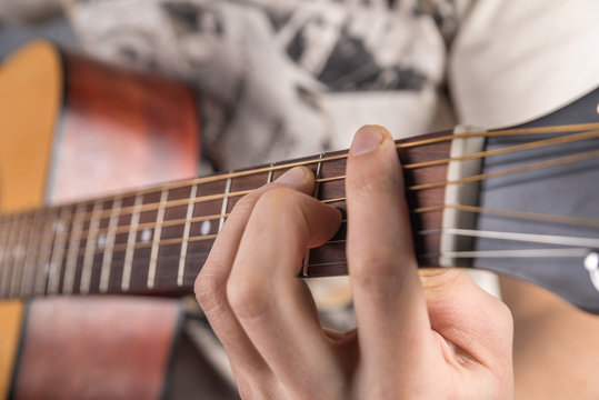 A picture of an acoustic guitar, classical color, in the hands of a guitarist