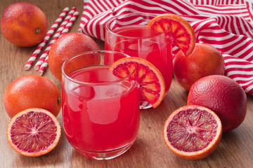 Red bloody oranges juice / Glass fresh juice drink and red bloody Sicilian oranges on wooden...
