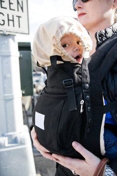 4 1/2 month old baby boy in baby carrier on street covered from sun