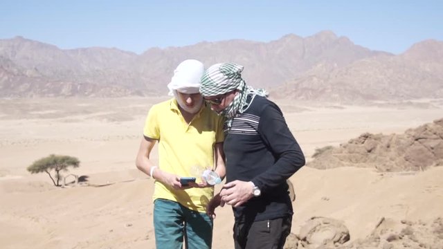 Son and father in the desert touching smart phone