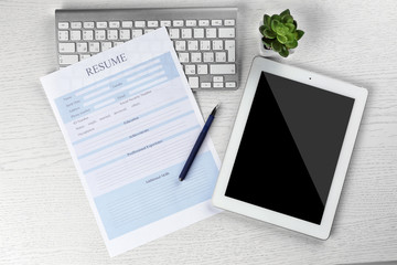 Resume, tablet and keyboard on wooden table