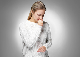 Young woman coughing on light background