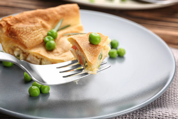 Piece of tasty chicken pot pie with green peas on plate, closeup