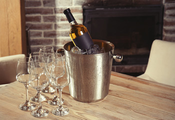 Wine bottle in bucket with ice and glasses on table © Africa Studio