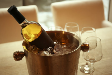 Wine bottle in bucket with ice and glasses on table © Africa Studio