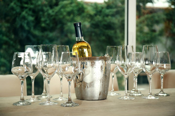 Wine bottle in bucket with ice and glasses on table © Africa Studio