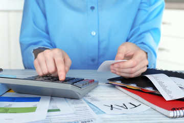 Woman sitting at table with calculator and bills
