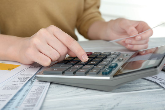 Woman sitting at table with calculator and bills
