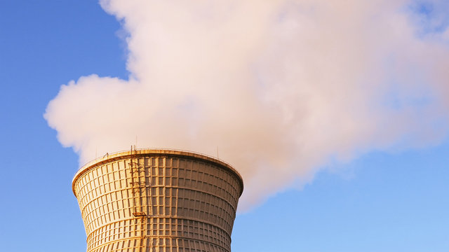 Water cooling tower stack smoke over blue sky background. Energy generation and air environment pollution industrial scene.
