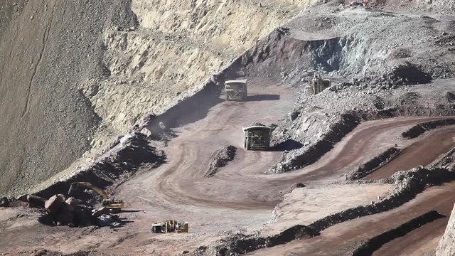 Heavy equipment digs and hauls ore inside an enormus open pit mine., Chile