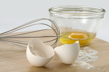 Baking Whisk and Eggs on Wooden Board