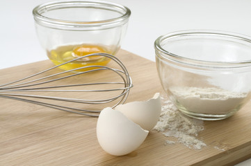Baking Whisk and Eggs on Wood Cutting Board
