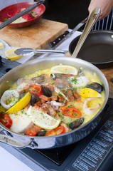 a seafood paella being cooked in a silver frying pan on a portable gas camping  stove