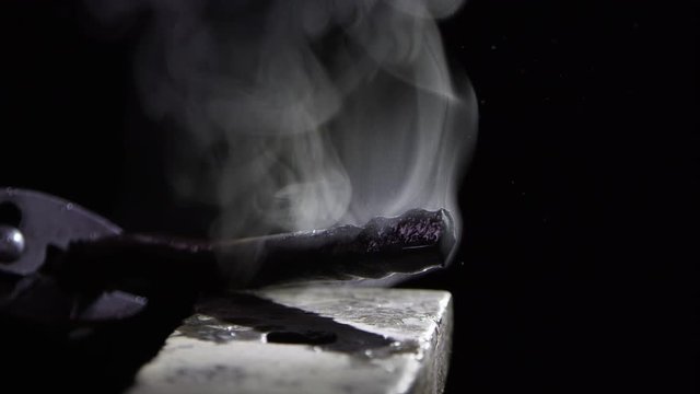 Piece of metal steaming being set on anvil.
