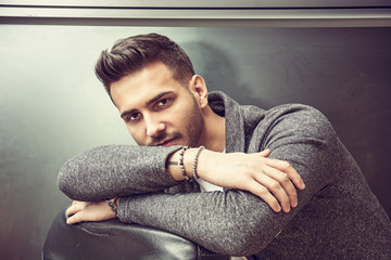 Handsome young man wearing grey sweater, on dark background