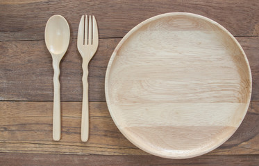 Top view shot of  handmade wooden spoon and fork beside plate.