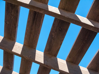 Blue sky as seen through weathered top of wooden pergola