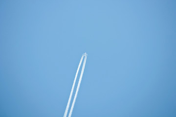 Белый след от реактивного самолета на ярком голубом небе