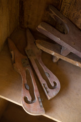 A dusty broken pair of antique wooden bellows in an all brown wooden setting.
