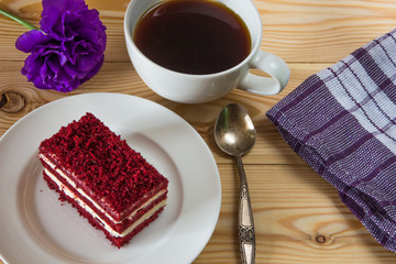 .Red velvet cake, cup of coffee and purple flower on wooden background