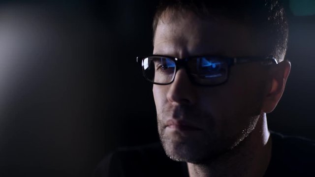 Portrait of a man close-up. Reflection of the monitor in glasses.