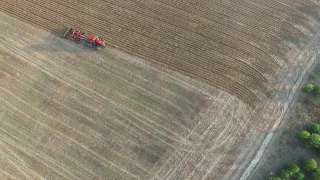 
4K Aerial. Tractor plough field in agriculture area, circle  flight
