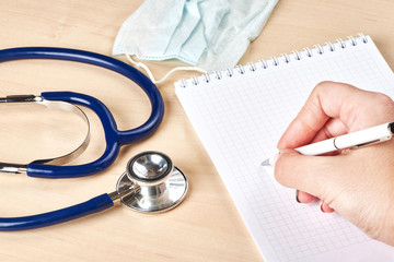 Doctor hand holding pen writing something on notebook
