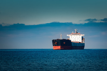 Black cargo ship moving in still Baltic sea water. Riga, Europe