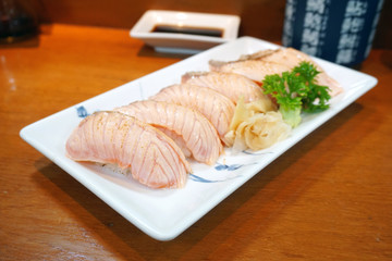 Closeup of salmon sushi on a white plate with salmon roe and chopped spring onion, Aburi style refers to nigiri sushi, the fish is partially grilled topside and partially raw - Japanese food style.