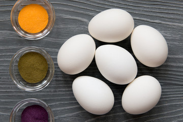 White chicken eggs and color pigments on a gray table. Celebrating Easter