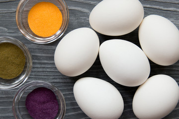 White chicken eggs and color pigments on a gray table. Celebrating Easter