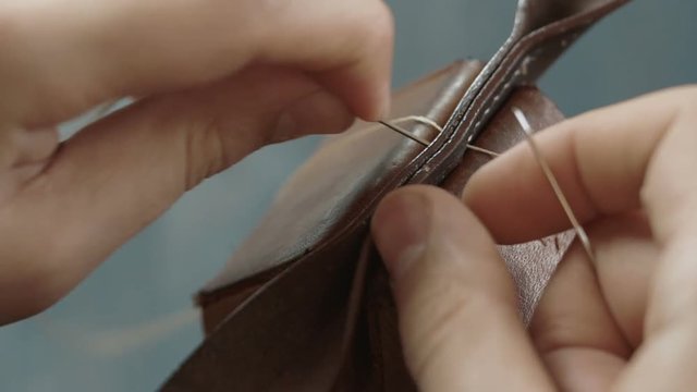 Closeup view of man's hand working with leather. Stitching leather manually. Handcrafts leather work.
