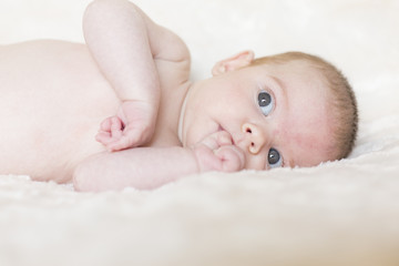 Portrait of  a cute baby girl awake, looking at the camera. White blanket background