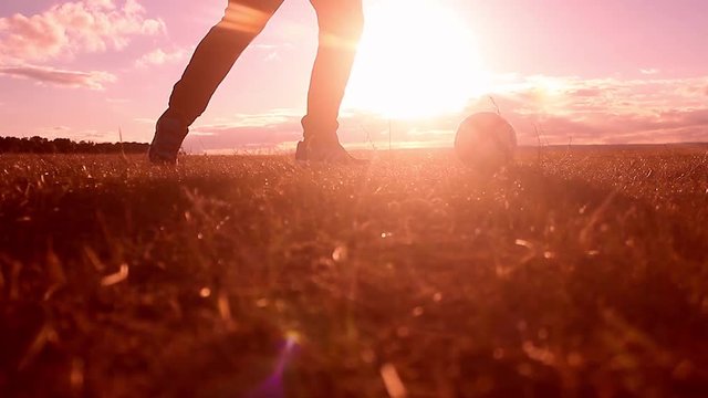 Beautiful sunset and silhouettes of men playing football, kick a soccer ball, goalkeeper catches ball. Silhouette of soccer player ready to execute penalty kick on the field.