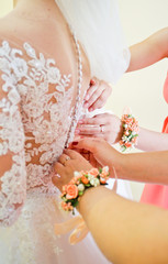 Wedding preparation in morning, bridesmaids helps bride, back of wedding dress with lace. A beautiful wedding morning