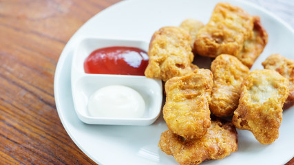 chicken nuggets, ketchup and mayonnaise on a white plate.