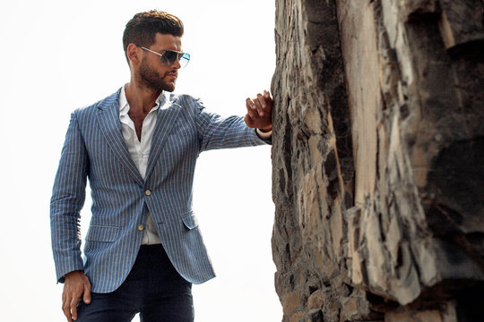 Man in elegant suite posing in rock background