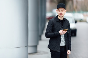 Fashionable man typing on his phone with blur background