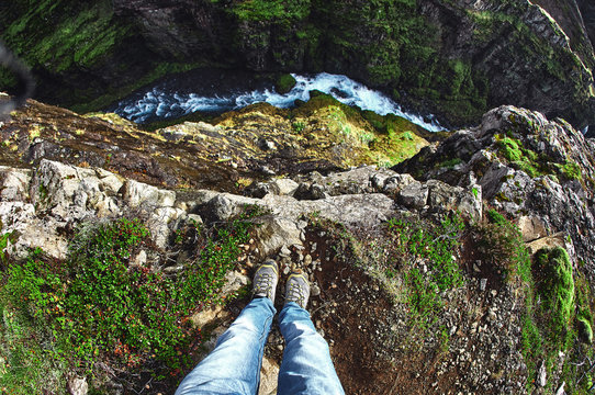 travel and Hiking to Iceland's highest waterfall - Glymur. hiker makes selfi by photographing his legs from above. A man is sitting on the edge of a cliff