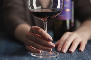 woman drinking alcohol on dark background. Focus on wine glass