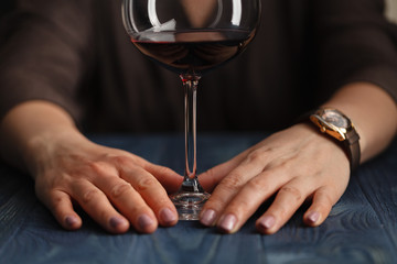 woman drinking alcohol on dark background. Focus on wine glass