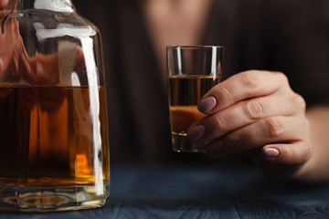Frau trinkt Alkohol auf dunklem Hintergrund. Fokus auf Weinglas