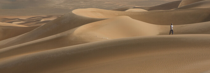 Fototapeta na wymiar young man walking in the sand dunes of Liwa desert