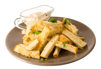 Croutons from white bread to beer with herbs and ketchup in a glass jug on green plate isolated on white background