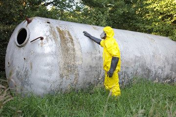 technician in uniform examining large stainless tank