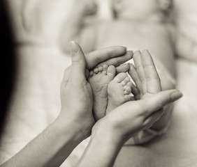 Mother holding tiny foot of newborn baby
