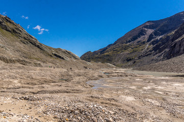 Wanderer laufen über das Geröll in einem Flußbett in den Bergen