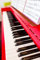 Fototapeta na wymiar Red piano with keys close-up with musical notes, nobody